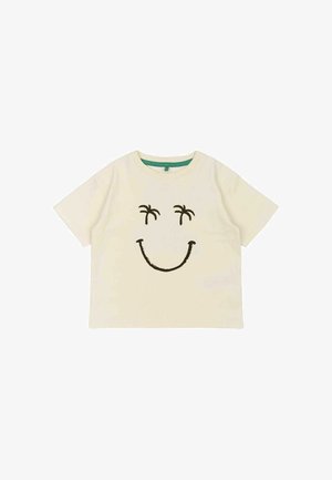 Crème-kleurige katoenen t-shirt met korte mouwen, voorzien van een groot zwart lachend gezicht ontwerp en twee palmbomenaccenten boven de ogen.