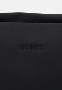 Sac en tissu noir avec le logo "HVISK" en relief, texture lisse, design épuré et style minimaliste sans matériel ou accents visibles.
