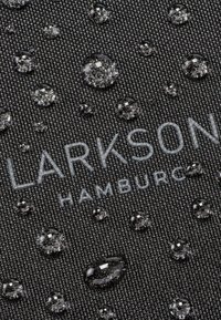 Fekete szövet, textúrált szövettel, vízcseppekkel elosztva a felszínen. "LARKSON" és "HAMBURG" világosszürkével nyomtatva.
