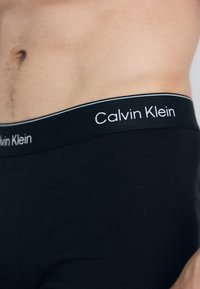 Zwarte katoenen boxershorts met een brede tailleband, voorzien van witte "Calvin Klein" branding en een fijne witte accentlijn.