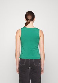 Top verde sin mangas hecho de tela suave. Presenta un escote redondo y un diseño ajustado. La vista trasera muestra una superficie lisa y sencilla.