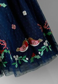 Fustă din tul bleumarin cu model cu puncte, având broderie colorată cu crenguțe de buxus, flori și pițigoi la tiv. Finisaj delicat, texturat.