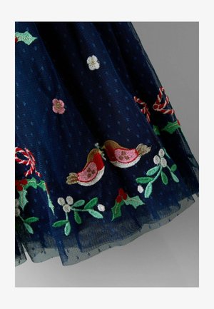 Laivastonsininen tüllihame, jossa on pilkkuprintti, ja helmassa värikästä kirjontaa metsämansikoista, kukista ja punarintaisista linnuista. Hienostunut, teksturoitu pinta.