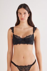 Soutien-gorge en dentelle noire avec bretelles réglables, motifs floraux, bords festonnés, et string en dentelle assorti avec des détails de design similaires.