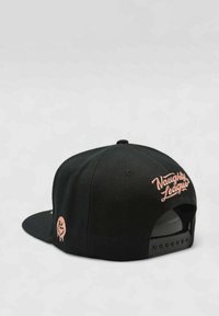 Musta snapback-lippalakki, jossa on vaaleanpunaisella brodeerattu teksti "Naughty League" takana, sileä materiaali ja rakenteellinen muotoilu.