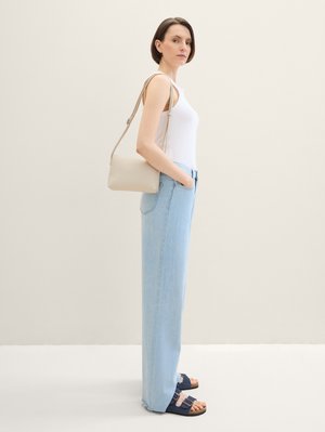 Lichtblauwe high-waisted jeans, witte fitted tanktop, marineblauwe sandalen met gespen en een beige schoudertas. Eenvoudig ontwerp en casual fit.