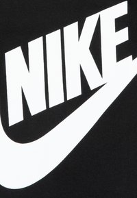 Svart stoff med en stor hvit "NIKE"-logo over en swoosh. Designet er dristig med klar kontrast, som fremhever logoen og merkeidentiteten.