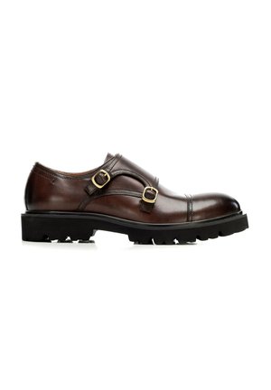 Chaussure monk strap en cuir marron foncé avec doubles boucles dorées et semelle épaisse en caoutchouc noir avec des rainures profondes, vue de côté.