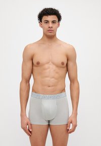 Grå boksershorts med en blå elastisk midjebånd som har teksten "ARMOR", laget av myk og stretchy stoff for komfort og passform.