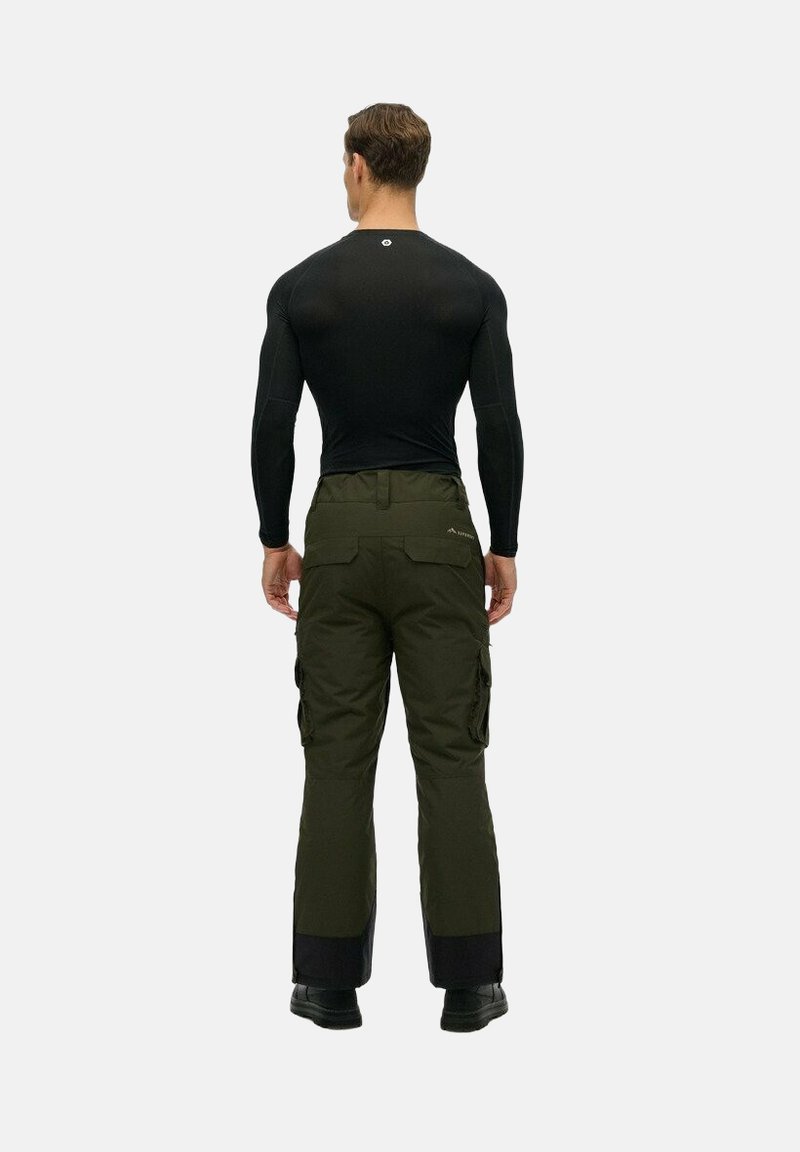 Zwarte langemouwen shirt en olijfgroene cargobroek met meerdere zakken, voorzien van een zwarte onderzoom en stevige zwarte schoenen.