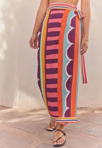 Multi-colored maxi skirt featuring bold stripes in purple, pink, orange, and teal, with scalloped details and a tied waist.