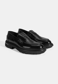 Schwarze Lederloafer mit abgerundetem Zeh, dekorativer Naht und robustem Gummisohle. Glatte Textur mit einem dezenten Glanz.