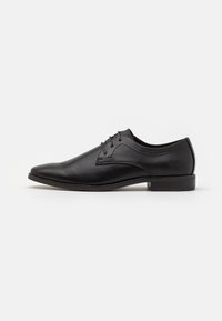 Chaussure habillée en cuir noir avec un bout pointu, un design à lacets et une texture lisse. Présente des coutures discrètes et un talon bas et plat.