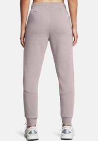 Helle rosa Jogginghose mit elastischem Bund, eng anliegenden Bündchen und Seitentaschen. Der Stoff wirkt weich und strukturiert. Trägt dazu weiße Sneakers.