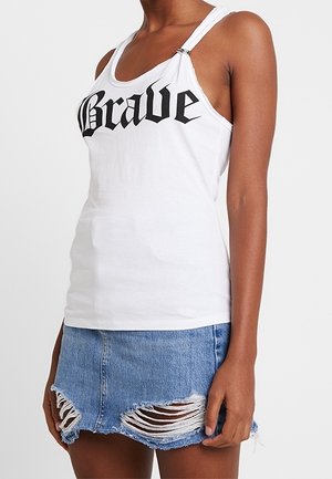 Débardeur blanc avec "Brave" imprimé en noir, doté de bretelles ajustables et d'un design ajusté. Assorti à une jupe en denim déchirée.