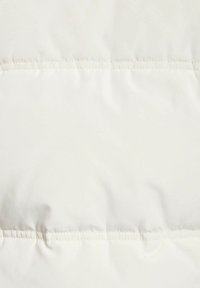 Giacca a sacco bianca con materiale morbido e opaco. Presenta cuciture visibili e un design elegante e senza soluzione di continuità.