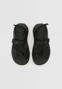 Sorte sandaler med justerbare stropper, tekstureret fodseng og en glat sål. Har et logo på indersålen og et minimalistisk design.