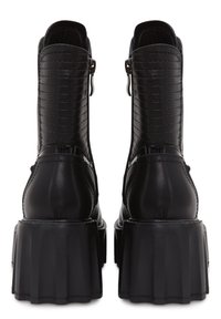 Bottines en cuir noir avec une semelle épaisse et évasée, fermeture éclair sur le côté et design de panneau texturé sur le dessus.