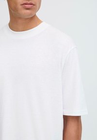 Hvid kortærmet t-shirt i blødt bomuldsstof. Har en rund halsudskæring og en afslappet pasform med let sænkede skuldersømme.
