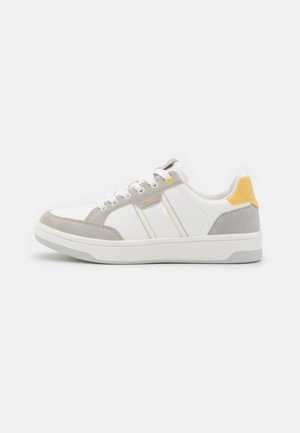 Biały niskoprofilowy sneaker z szarymi zamszowymi nakładkami, żółtym akcentem na pięcie, białymi sznurowadłami i subtelnym logo marki z boku.