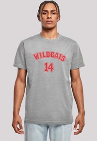 Pilkas medvilninis marškinėliai su raudonu užrašu "WILDCATS" arkine forma virš antrojo numerio "14" drąsiu šriftu. Trumpomis rankovėmis, apvaliu iškirpimu, laisvai krintantis siluetas.