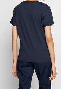 Marineblå bomulds T-shirt med rund hals, korte opkrøllede ærmer og lige snit. Har et ensfarvet design og blød tekstur, med minimal syning.