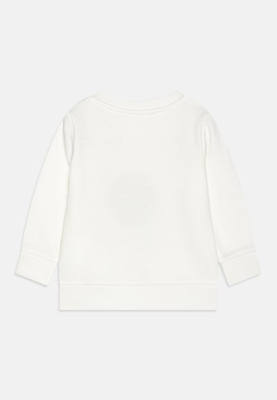 Balta džemperis su ilgomis rankovėmis, su raukšlėmis rankogaliuose ir apačioje. Turintis apvalią iškirptę ir minkštą, tekstūruotą audinį be jokio papuošimo.