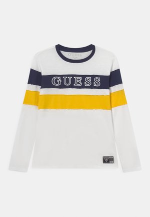 Weißes Langarmshirt mit marineblauen und gelben horizontalen Streifen über Brust und Armen, mit dem Schriftzug "GUESS" auf dem marineblauen Streifen.