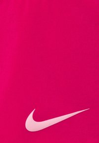 Kirkas vaaleanpunainen Nike-kangas, jossa on sileä pinta, ja vasemmassa alakulmassa on suuri valkoinen Nike-swoosh-logo.