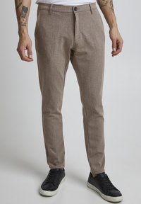 Ruske teksturoidut housut slim fit -mallissa, napituksessa ja taskuissa, yhdistettynä mustiin lenkkareihin, joissa on valkoinen pohja.