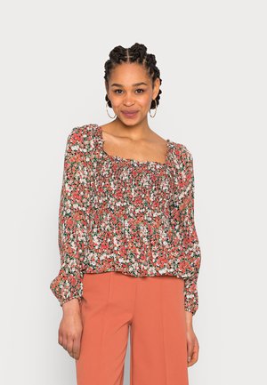 Blusa floral com decote quadrado, mangas bufantes e cintura franzida. Estampa floral vermelha e verde sobre um fundo claro. Tecido leve.