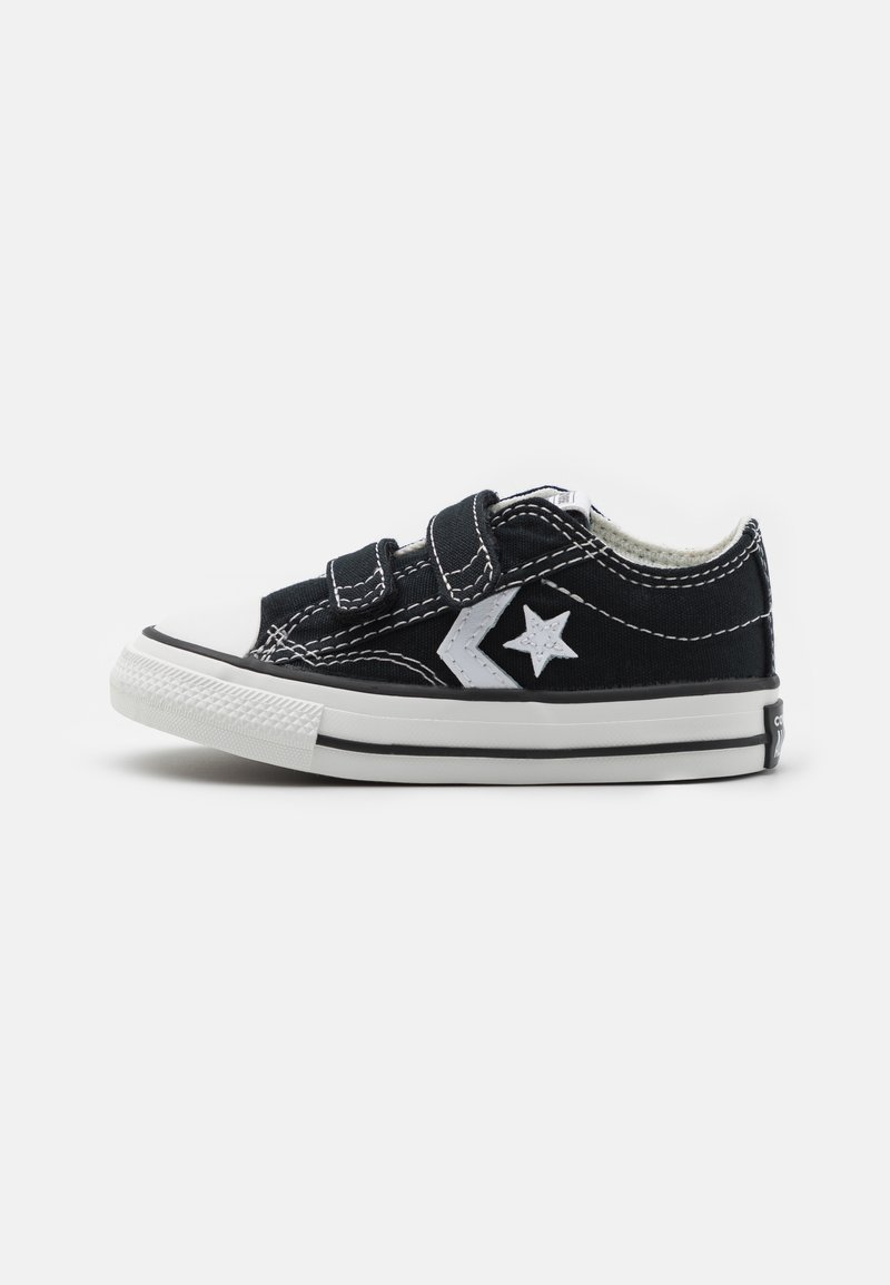 Sorte kanvas sneakers med hvit gummisåle og tåhette, med to borrelåser og et hvitt stjernemotiv på siden.