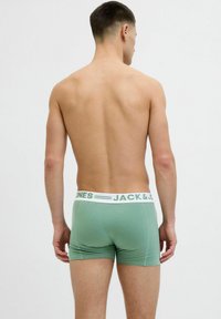 Grüne Baumwoll-Boxershorts mit einem weißen elastischen Bund, auf dem der Text "JACK & JONES" abgedruckt ist. Angenehme Textur, enganliegendes Design und mittelhoher Schnitt.