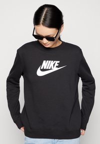 Felpa nera Nike con logo bianco sul petto, caratterizzata da maniche lunghe e colletto rotondo, realizzata in morbido tessuto di cotone.