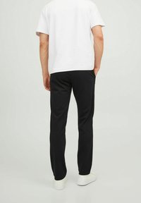 Černé kalhoty s volným střihem, vyrobené z měkké tkaniny. Kombinované s jednoduchým bílým tričkem a bílými teniskami. Jednoduchý design, minimální akcenty.