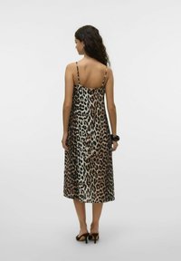 Abito con stampa leopardata, spalline sottili, lunghezza a metà polpaccio e una texture liscia. I colori dominante sono il beige e il nero.