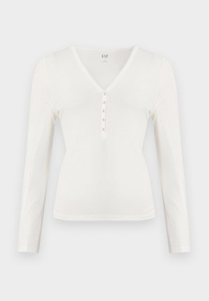Bílá tričko s dlouhým rukávem a výstřihem do V, s měkkou texturou a pěti knoflíkovým zapínáním. Má přiléhavý střih a jemné šicí detaily.