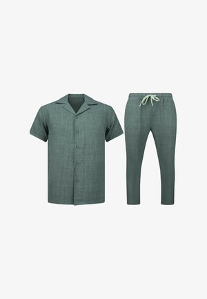 Kort mouwen blouse met knopen en kraag en bijpassende broek met trekkoord in gestructureerde groene stof op een witte achtergrond.