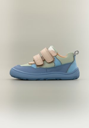 Zapatilla infantil de color verde claro y azul con dos tiras de velcro beige y una lengüeta para tirar, sobre un fondo neutro.