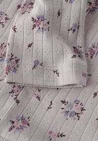 Lichtgrijs, geribbeld textiel met kleine, meerkleurige bloemenpatronen in roze en blauw; zachte textuur met zichtbare stikdetails.