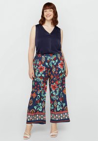 Blusa senza maniche di colore blu navy abbinata a pantaloni a gamba larga con un vivace motivo floreale. I pantaloni presentano una cintura elastica e bordi decorativi.