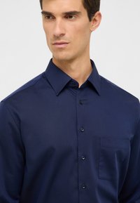 Marineblauwe button-up shirt met een klassieke kraag, borstzak en een gladde textuur. Beschikt over vijf knopen aan de voorkant en lange mouwen.