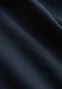 Dunkelblauer Stoff mit einer glatten, leicht strukturierten Oberfläche. Subtiles geripptes Muster, ideal für verschiedene Textilanwendungen.