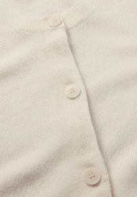 Weißer Cardigan aus weichem Strickstoff, mit rundem Ausschnitt, fünf Knöpfen vorne und subtiler Struktur.