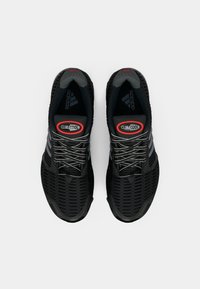 Chaussures de sportnoires avec une tige en maille, présentant des rayures grises, une semelle texturée et un logo CLIMACOOL rouge sur la languette.