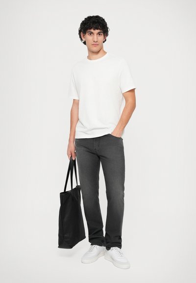 Camiseta de algodão branca combinada com calças de ganga cinza-escuro e ténis brancos. Segura uma mala tote preta. Design simples, sem padrões ou logótipos visíveis.