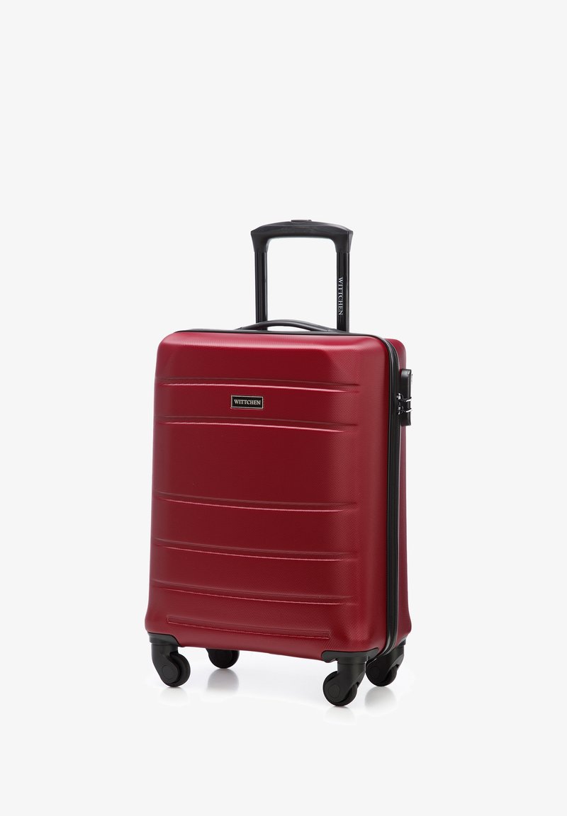 Maleta dura roja con superficie texturizada, cremallera negra y asa. Cuenta con cuatro ruedas para movilidad y un diseño compacto.