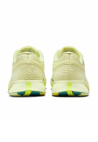 Zapatillas deportivas de color amarillo claro con parte superior de malla texturizada y acentos verdes. Cuentan con una suela resistente con patrones coloridos y una lengüeta en el talón.