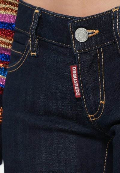 Vaqueros de mezclilla azul oscuro con costuras en contraste, cierre de botón plateado y una etiqueta roja DSQUARED2 visible en la cintura.