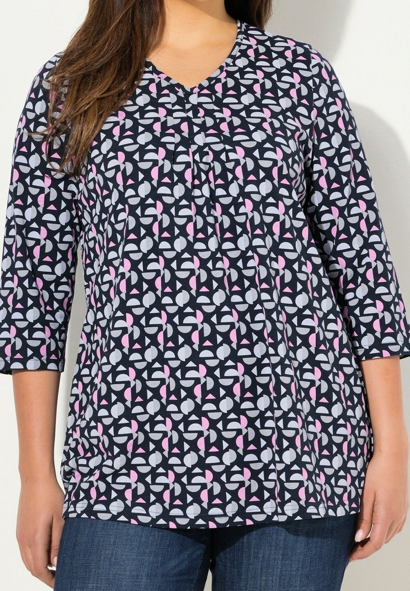 Granatowa bluzka z dekoltem w serek, z rękawami 3/4, z geometrycznym wzorem w odcieniach różu i szarości. Miękki materiał o luźnym kroju.